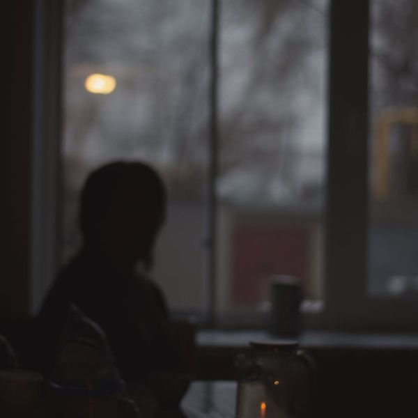 Silhouette of a person meditating against a dark, serene background with a subtle glow.